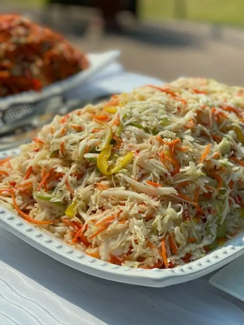 A large serving of coleslaw with shredded cabbage, carrots, and green peppers on a white rectangular plate.